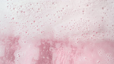 Water wave flows creating a lot of foam on pink background
