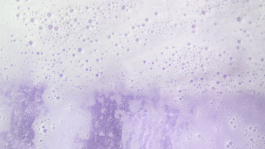 Water wave flows creating a lot of foam on violet background