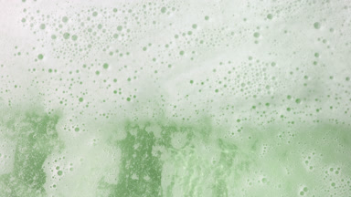 Water wave flows creating a lot of foam on green background