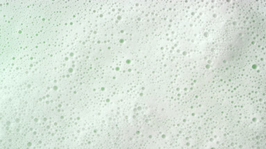 Macro shot of water with a lot of foam flows on green background