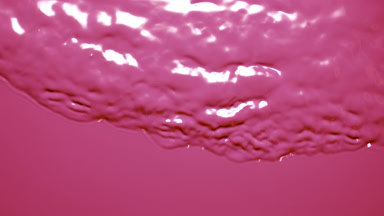 Macro shot of small waves on pink opaque liquid surface