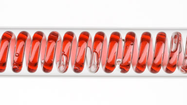 Red liquid in horizontal coil condenser, white background view