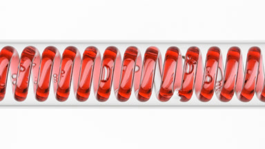 Red liquid in horizontal coil condenser on white background