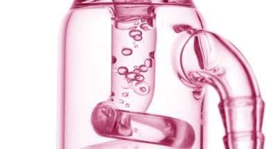 Clear liquid bubbles condense in glass tube, white background