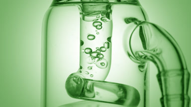 Clear liquid bubbles condense in glass tube, green background