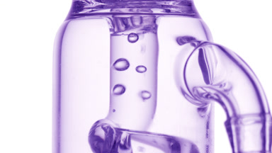 Transparent liquid bubbles condense in glass tube, white bg