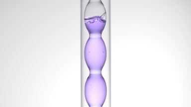Pale violet liquid in bulb condenser on light grey background