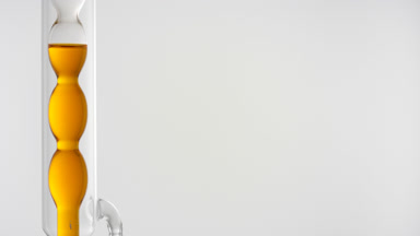 Orange liquid drains from vertical bulb condenser, grey scene