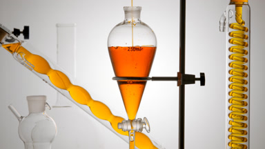Glycolic acid solution pours into funnel, bubbles, flows in coil