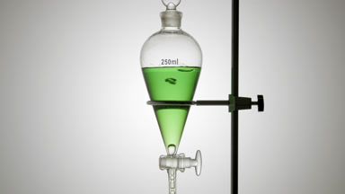 Green liquid drips from separatory funnel, bubbles rise, grey