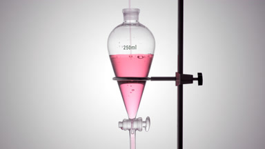 Strawberry distillate poured in funnel, bubbles rise underwater