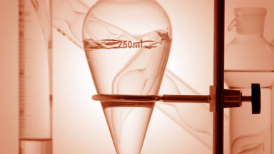 Clear liquid injected, waves in flask on beige background