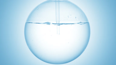Mineral water dropper into round flask, swirling bubbles effect