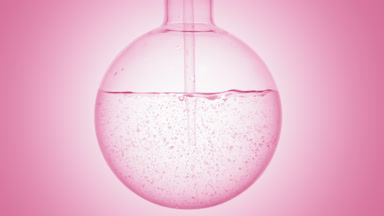 Pink liquid dropper into round flask, swirls & bubbles, pink bg