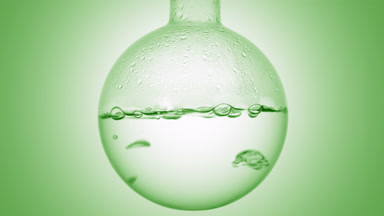Clear liquid boiling in flask, condensation on green ramp bg