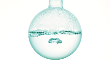 Clear liquid boiling in flask, condensation on white bg