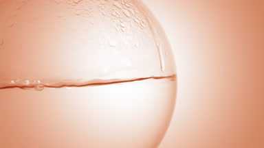 Clear liquid boiling in flask, bubbles on beige ramp background