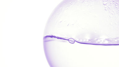 Clear liquid boiling in flask, bubbles and condensation white