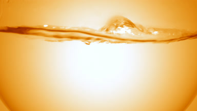 Clear liquid boiling in flask, bubbles and waves, orange bg