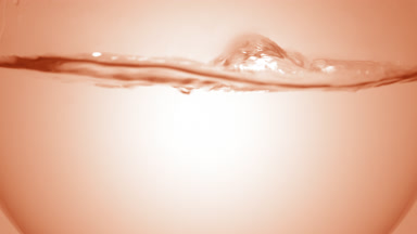 Clear liquid boiling in flask, bubbles and waves, beige bg
