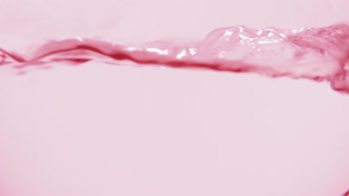 Pink liquid boiling in flask, bubbles and waves, pink bg