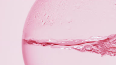 Pink liquid boiling in flask, bubbles, waves, condensation