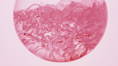 Pink liquid boiling in flask, bubbles on pale pink bg