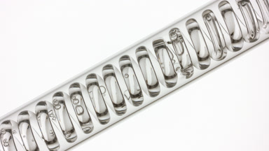 Clear liquid in inclined coil condenser on white, filling up