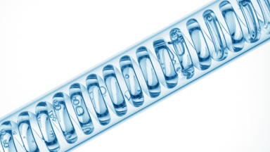 Pale blue liquid in inclined coil condenser on white, filling