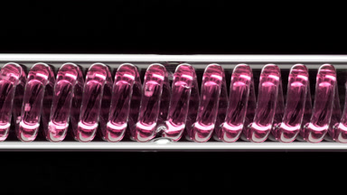 Pink liquid flowing in horizontal coil condenser on black