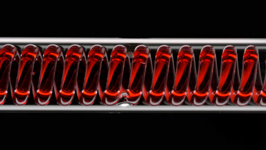 Red liquid in horizontal coil condenser on black background