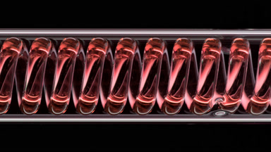 Red liquid in horizontal coil condenser on black background