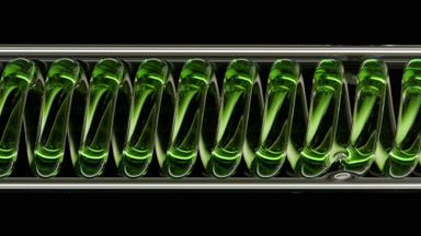 Green liquid in horizontal coil condenser on black background