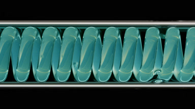 Cyan liquid in horizontal coil condenser on black background