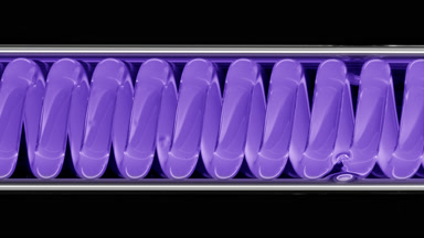 Violet liquid in horizontal coil condenser on black background