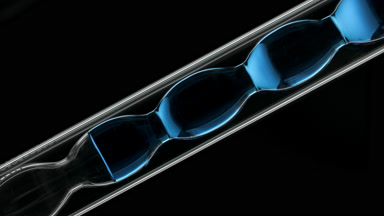 Blue liquid inside inclined bulb lab condenser, black background