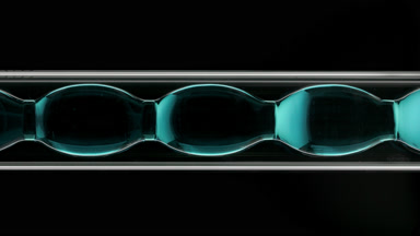 Cyan transparent liquid in vertical bulb condenser, black bg