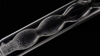Clear liquid condensing on bulb lab condenser, black background