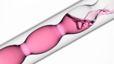 Rose hydrosol pouring into inclined bulb condenser in lab scene