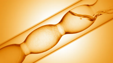 Liquids of varying density mixing in lab flask, swirls on yellow
