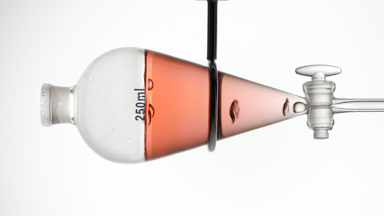 Reddish transparent liquid with rising bubbles, grey backdrop