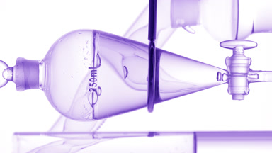 Clear liquid drains from funnel, bubbles rise on white backdrop