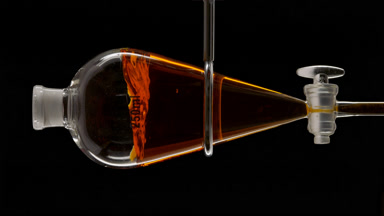 Saffron infusion injected creating golden splashes in the funnel