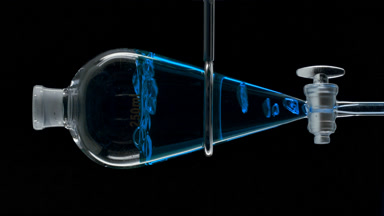 Blue liquid forms rising bubbles on black, dynamic view