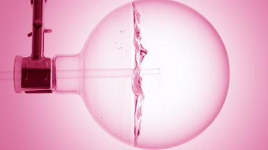 Pink liquid dropper into round flask, swirls & bubbles, pink bg