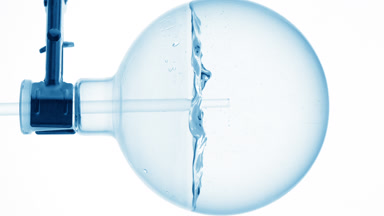 Micellar water dropper into round flask, swirling bubbles effect