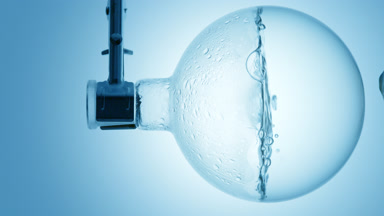 Clear liquid boiling in flask, condensation on blue ramp bg
