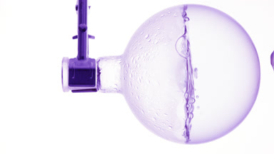 Clear liquid boiling in flask, condensation on white bg