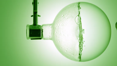 Clear liquid boiling in flask, condensation on green ramp bg