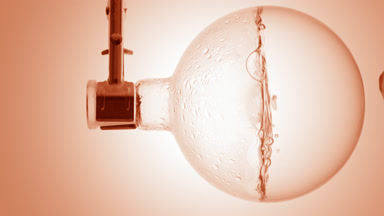 Clear liquid boiling in flask, condensation on beige ramp bg